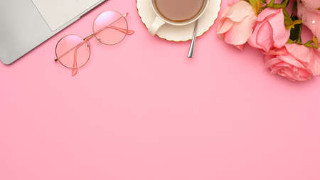 Copy space for product display or presentation background with laptop, eyeglasses, teacup and roses on pink background. top viewの写真素材