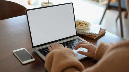 A female typing on portable laptop computer, remote working at cozy cafe, doing her online...
