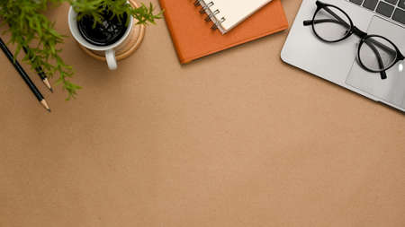 A brown workspace background with office supplies, laptop computer, eyeglasses, coffee cup and copy space for product display. top viewの写真素材