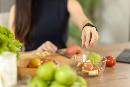 Close-up image, A woman preparing healthy food ingredients, chopping apples, making a salad bowl in the kitchen.の写真素材