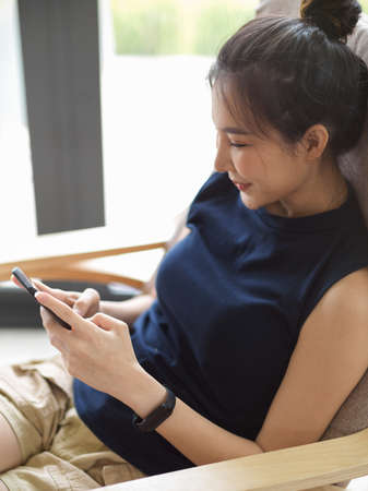 Close-up, rear view, Woman spends her free time at home, socializing with her friends via a mobile...