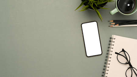 Study table background with stationery, decor, smartphone white screen mockup and copy space on grey background. top viewの写真素材