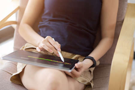 Close-up image, Female entrepreneur remote working at her home, analysing and checking her stock investment on tablet computer.の写真素材