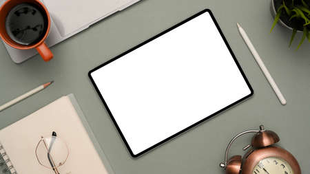 Modern workspace with notepad, glasses, coffee cup, stylus pen, laptop, vintage clock and tablet white screen mockup for display your graphic on screen over grey background. top viewの写真素材