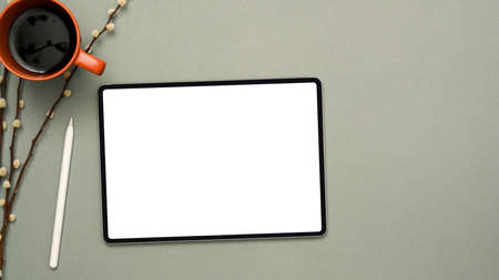 Mockup screen of digital tablet touchpad for montage graphic display with stylus pen, coffee cup and dried flowers on grey background. top viewの写真素材