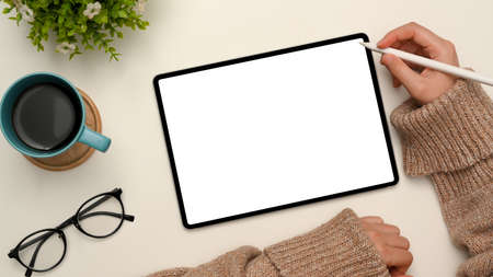 Female holding stylus pen and sketching something on digital tablet. Tablet white screen mockup with accessories on white background. top viewの写真素材