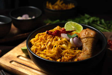 Khao Soi Kai, Northern Thai coconut yellow curry soup with chicken and egg noodles top with...