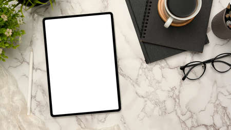 Modern workspace with portable tablet computer white screen mockup and office supplies on marble...