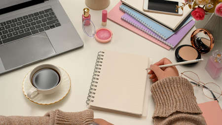 Close-up image, Female beauty blogger or college student taking notes on spiral notepad at her stylish office desk. Empty spiral notepad paper for display your text.の写真素材
