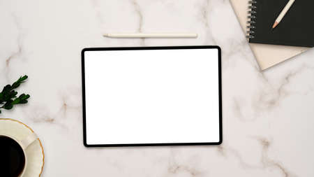 Minimal white marble office desk background with portable tablet empty screen mockup, stylus pen, notebooks, and decor. top view, flat layの写真素材