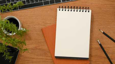 Top view, Classic wooden worktable or study table with empty spiral notepad for display your text and office accessories.の写真素材