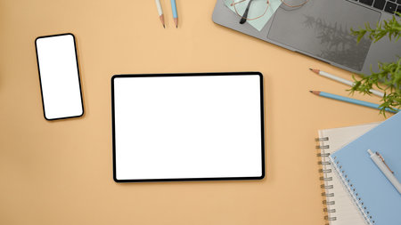 Workspace in beige background with smartphone white screen, tablet empty screen and office supplies.の写真素材