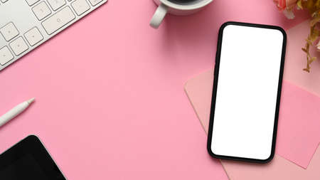 Overhead shot, Pink workspace background with smartphone blank screen mockup, keyboard, coffee cup,...