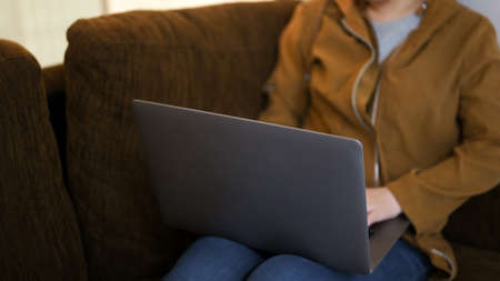 A female relaxed in home living room, using portable laptop computer on the comfy sofa. close-upの写真素材