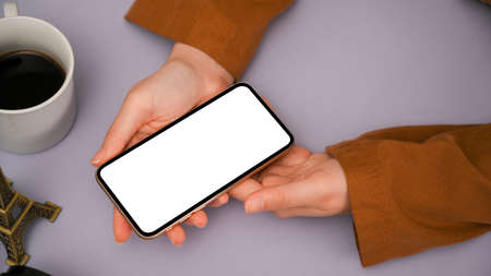 Close-up image, A girl using her modern smartphone over her pastel purple study table workplace. phone blank screen mockup.の写真素材