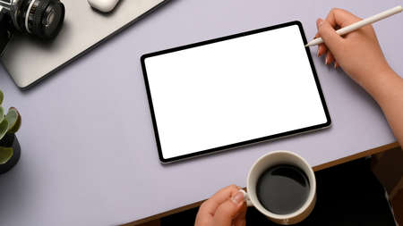 Cropped, closeup top view image of a woman hand holding a cup coffee and drawing something on...