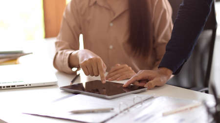 Businesswoman and businessman brainstorming and looking the details at tablet screen in the office.の写真素材