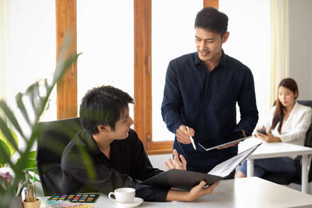 Two businessmen are talking and sharing their ideas for the marketing project in office workplace.の写真素材