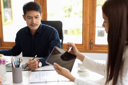Concentrated male graphic designer or photo editor brainstorming in the office with female colleague