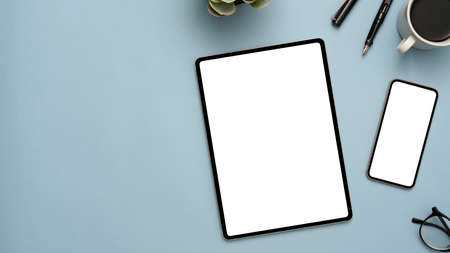 Pastel blue workspace background with tablet and smartphone white screen mockup, office accessories and copy space. top viewの写真素材