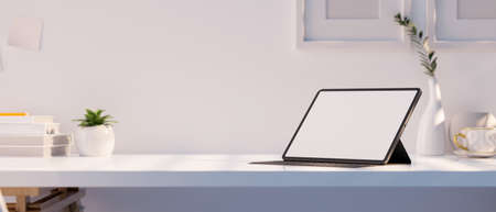 Modern white office desk with portable tablet touchpad white screen mockup, office accessories and copy space for product display against white wall. 3d rendering, 3d illustrationの写真素材