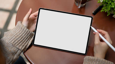 Close-up, Female in cozy knitted sweater using smart tablet touchpad, tablet white screen mockup.