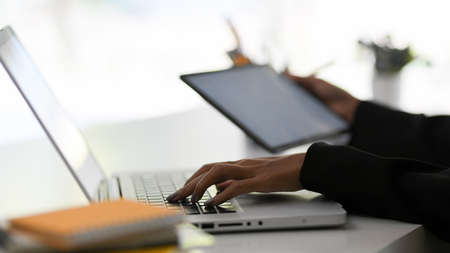 Close-up image, Female employee or businesswoman typing the report on laptop computer at her office desk. Focus hands.の写真素材