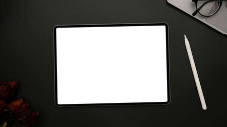 Modern digital tablet white screen mockup on black background with stylus pen, roses, laptop and...