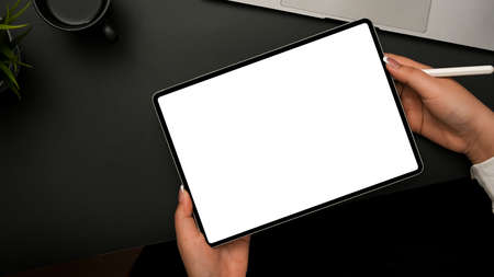 Overhead shot, Female hands holding digital tablet touchpad empty screen mockup and stylus pen over...