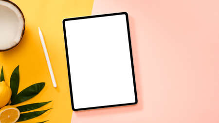 Tablet touchpad white screen mockup on a creative colourful background with summer tropical fruits....