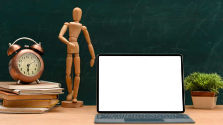 Student workspace background with laptop computer blank screen mockup, vintage clock, stack of books and decor against chalkboard background.の写真素材
