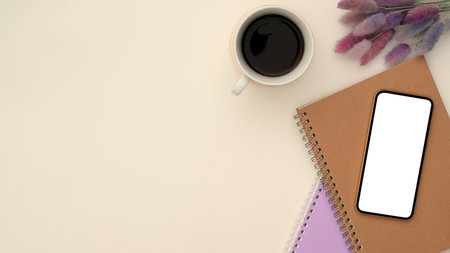 Top view, Modern white and purple workspace compositions with smartphone white screen mockup, notepad, a cup of coffee, purple flowers and copy space on white background.の写真素材
