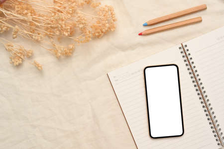 Minimal white workspace background with smartphone mockup, stationery and dried flowers. top viewの写真素材