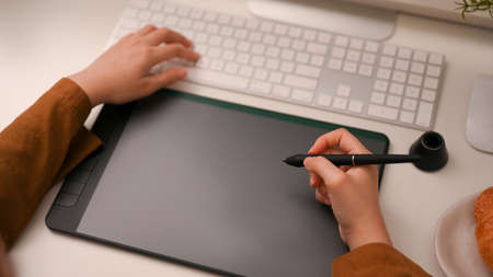 Close-up image, Female freelance graphic designer or photo editor using on graphic tablet and...