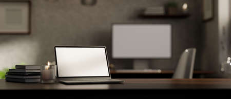 Dark wood tabletop workspace with notebook laptop white screen mockup, candle, book and copy space...