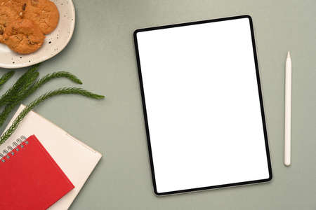 Modern minimal office desk with book, a plate of cookies, stylus pen and digital tablet white screen mockup on grey background.の写真素材