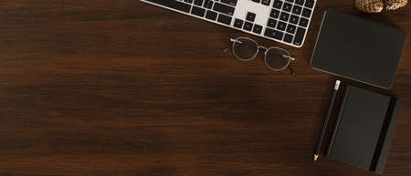 Overhead shot, Dark wooden office table background with copy space, keyboard computer, notebook, glasses and accessories. 3d rendering, 3d illustrationの写真素材