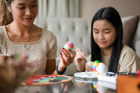 Happy Easter holiday moment concept, Two pretty sisters painting an Easter egg together at home.の写真素材