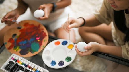 Cropped image, Two sisters spending time on Easter holiday together at home, enjoy painting Easter egg. Easter egg concept.の写真素材