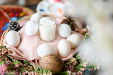 Happy Easter eggs with white candle on a beautiful basket decorated with plenty of beautiful flowers