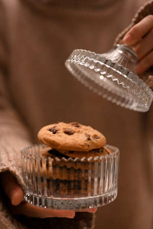 Close-up image, Female in warm sweater open a cookies jar. Homemade chocolate chip cookies.の写真素材