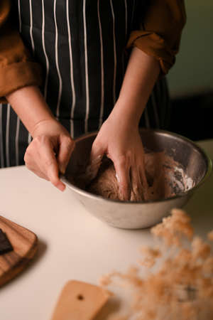 Close-up, Female hand kneading cookies dough in a mixing bowl. Homemade pastries cookies concept.の写真素材