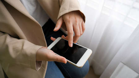 Top view, Female in minimal beige suit using smartphone to contact with her business clients.