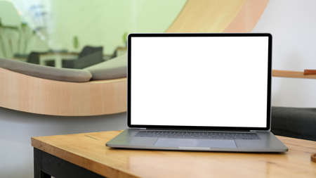 Open laptop computer white screen mockup for display your graphic banner in on wooden worktable.