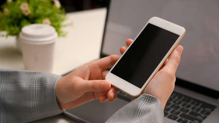 Close-up, Businesswoman in formal suit using smartphone over her office table. phone black screen.