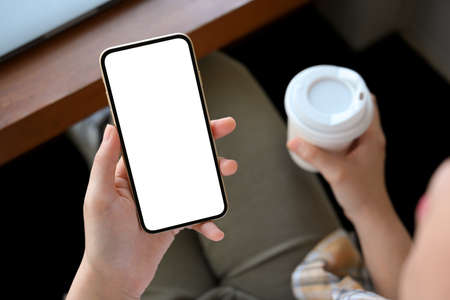 Relaxed woman sitting in the coffee shop, sipping coffee while using her smartphone. phone white...