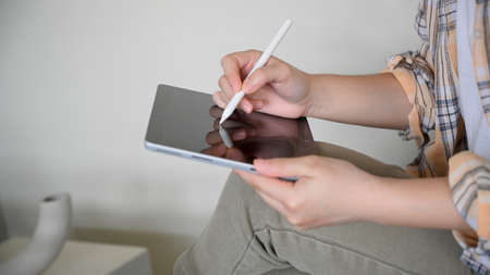 Close-up, Female freelancer in Scott shirt remote working at cafe and using tablet with stylus pen.