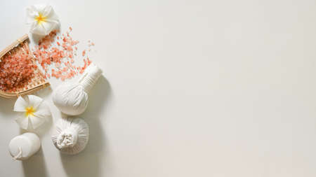 Thai spa massage treatment background, Spa herbal balls or massage stamps, pink salt, frangipani flowers and copy space on white background.の写真素材