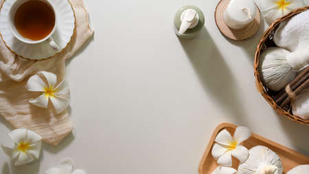Organic Thai spa massage treatment background with organic massage products, spa herbal balls, massage oil, herbal tea, frangipani flowers and copy space on white background.の写真素材