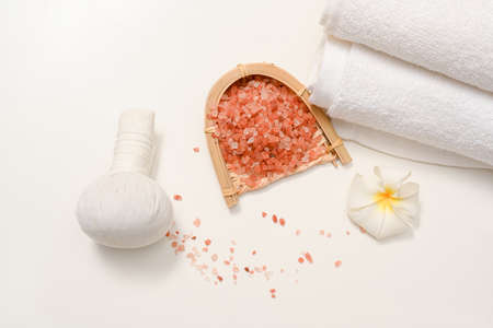 Spa compositions with Himalaya salt, massage ball, towels and frangipani flower on white background.の写真素材